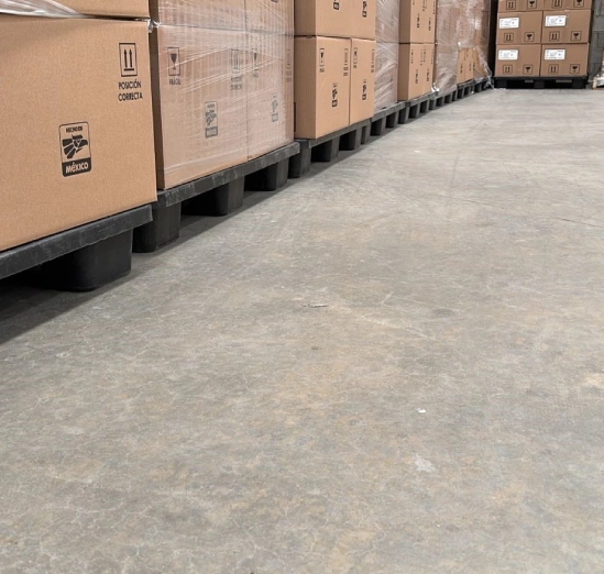 Rows of stacked cardboard boxes on pallets in a warehouse aisle.
